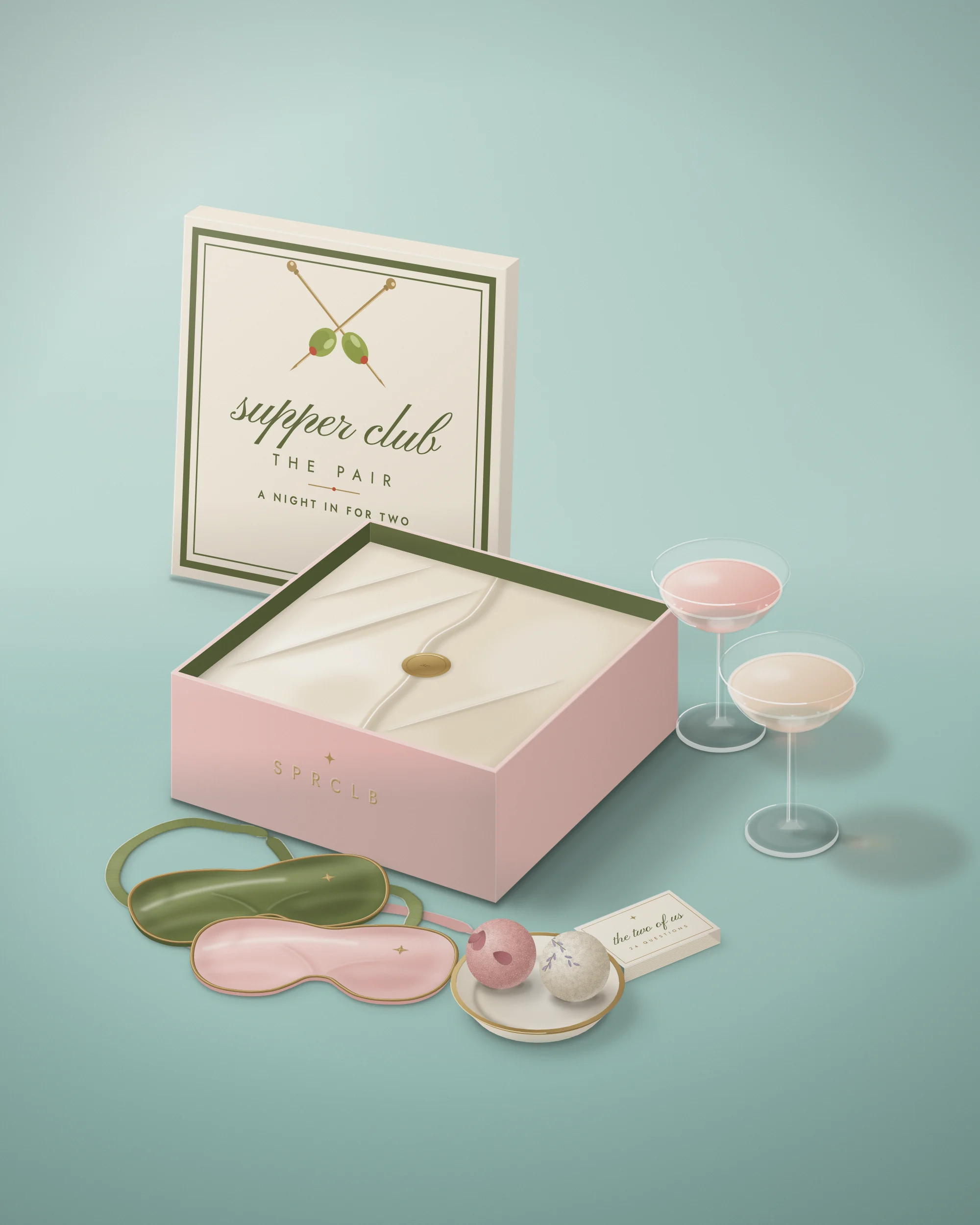 The Pair: the box open on a pale pool-blue backdrop with two satin eye masks, two bath bombs, a deck of questions for two and two coupes